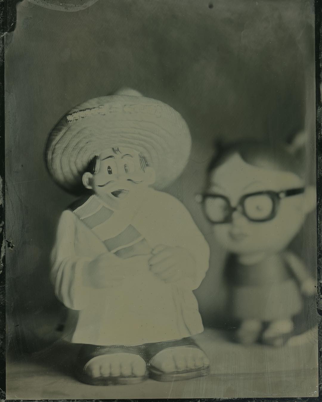 Pedro and Little Enid. 
I brought some toys to the wet plate workshop @penumbrafoundation taught by the amazing @elmalayheehoo to use for still lifes. This one features the mascot of everyoneâs favorite racist tourist trap, South of the Border, and the main character from the movie and graphic novel Ghost World. #tintype #wetplate #wetplatecollodion #makeyourownfilm  #largeformat #4x5